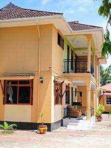 uma casa amarela com uma varanda em Jm Lodge - Kunduchi em Dar es Salaam