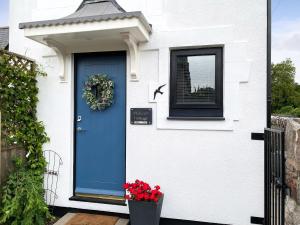 una porta blu su una casa bianca con una finestra di Swallows Cottage a Churston Ferrers