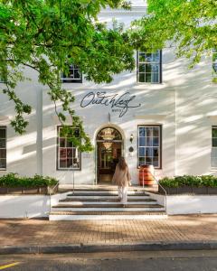 a woman walking into a white building at Oude Werf Hotel in Stellenbosch