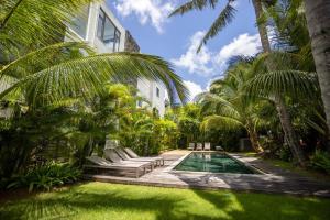 a house with a swimming pool and palm trees at Bayview Apartment Grand Bay in Grand Baie