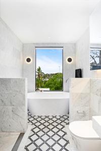 a white bathroom with a tub and a window at Luxury Waterside Home in Sydney