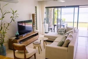 a living room with a couch and a flat screen tv at Bayview Apartment Grand Bay in Grand Baie