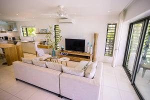 a living room with a white couch and a tv at Bayview Apartment Grand Bay in Grand Baie