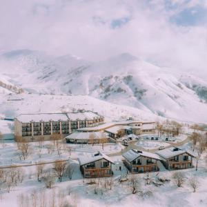 a building covered in snow in front of a mountain at Marco Polo Hotel Gudauri in Gudauri