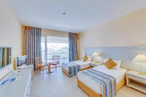 a hotel room with two beds and a desk at The Grand Blue Sky International - All Inclusive in Kuşadası