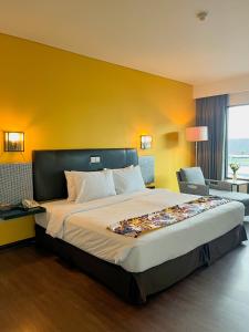1 dormitorio con 1 cama grande y pared amarilla en Horison Ultima Bandara Balikpapan en Sepinggang-Kecil