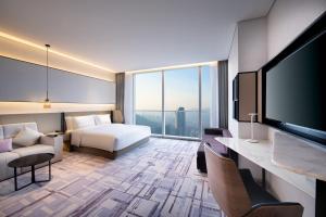 a hotel room with a bed and a flat screen tv at Crowne Plaza Dalian Xinghai, an IHG Hotel in Dalian