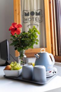 uma mesa com um bule de chá e uma taça de fruta em Hotel Mom Assisi em Assis