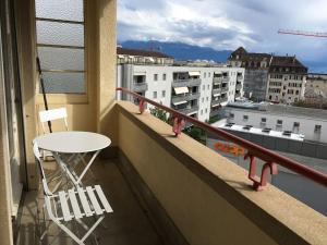 une chaise blanche assise sur un balcon avec une table dans l'établissement La proximité du centre avec vue sur le lac., à Lausanne