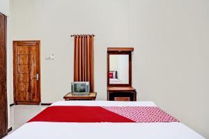 a bedroom with a bed and a mirror and a tv at OYO 92367 Garuda Homestay Syariah in Banyuwangi