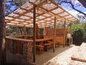 een houten pergola met een houten tafel en banken bij Gaia Off-grid Campsite in Swellendam