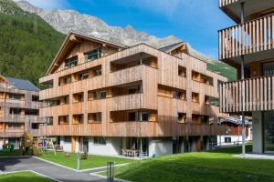 um edifício de madeira com montanhas ao fundo em Montela Hotel & Resort - Suiten em Saas-Grund