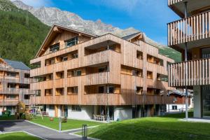 a wooden building with mountains in the background at Montela Hotel & Resort - Suiten in Saas-Grund