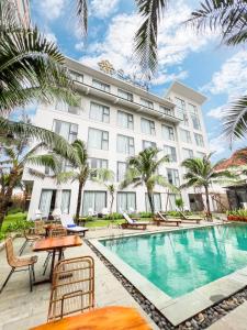 um hotel com piscina e palmeiras em Sala Tuy Hoa Beach Hotel em Tuy Hoa