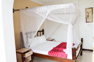 - une chambre avec un lit à baldaquin et une couverture rouge dans l'établissement Bridge Hotel Mombasa, à Mombasa