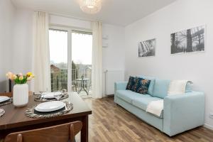 a living room with a blue couch and a table at Stacja Wola Apartments with Parking by Renters in Warsaw
