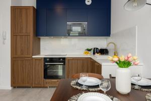 a kitchen with blue cabinets and a table with a vase of flowers at Stacja Wola Apartments with Parking by Renters in Warsaw