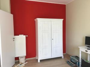 a room with a white cabinet and a red wall at die Senfbude - schöne, ebenerdige 2-Raum-Apartments mit Stellplatz und Terrasse in Leipzig