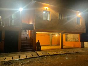 a man sitting in front of a building at night at Résidence Karamel Yaoundé Anguissa in Yaoundé