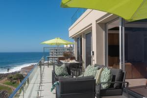 a balcony with chairs and a table and an umbrella at Ballito Sands Penthouses in Ballito