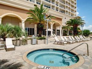 Una piscina frente a un hotel con sillas y un edificio. en Beach Club #1804C, en Pensacola Beach
