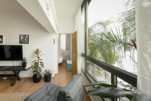 uma sala de estar com um sofá e uma grande janela em Cozy 2BR Apt w Green Oasis a 3 Min Walk from Beach by Sea N' Rent em Tel Aviv