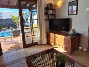 a living room with a flat screen tv and a patio at Villa de la Paz in Playa Blanca