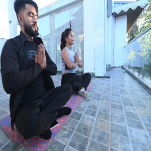 un hombre y una mujer sentados en el suelo haciendo yoga en Amaira Resort & Farms - Mirik, West Bengal en Mirik