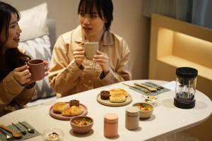 two women sitting at a table looking at a cell phone at hotel hisoca ikebukuro in Tokyo