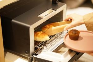 a person taking a muffin out of a toaster oven at hotel hisoca ikebukuro in Tokyo