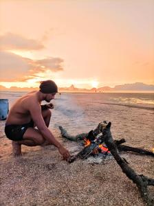Er staat een man op het strand te koken boven een kampvuur. bij KRABI BAMBOO KINGDOM at AOLUEK PARADISE in Ao Luk