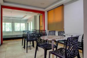 jadalnia ze stołami, krzesłami i oknami w obiekcie Treebo Trend Vetri Supreme Residency w mieście Ćennaj