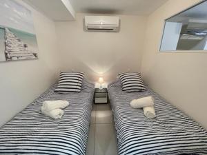 two beds in a room with pillows on them at Appartement Vue Mer Golfe de Saint-Tropez in Sainte-Maxime