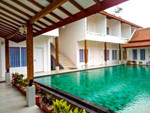 a swimming pool in front of a house at Sinom Borobudur Heritage Hotel in Borobudur