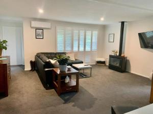 a living room with a couch and a tv at Tynedale Cottage Bowral in Bowral