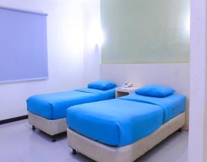 two beds in a room with blue pillows at Suzuya Hotel Bagan Batu in Bagansinembah