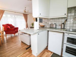 a kitchen with white cabinets and a living room at Peacehaven in Liskeard