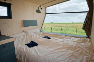 Bett in einem kleinen Zimmer mit einem großen Fenster in der Unterkunft Sleep Space 21 - Green Tiny Village Harlesiel in Wittmund