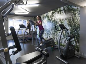 a woman in a gym with a painting on the wall at Hôtel Cofortel in Quebec City