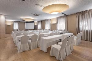 une salle de conférence avec des tables et des chaises blanches dans l'établissement Eurostars Vía de la Plata, à Astorga