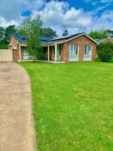 uma casa de tijolos com um relvado verde em frente em Tynedale Cottage Bowral em Bowral