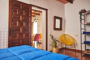1 dormitorio con 1 cama azul, puerta y sillas en Cortijo El Guarda, en Almería