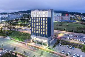 um edifício alto com luzes acesas numa cidade em Jeju Pureun Hotel em Seogwipo