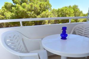 Una botella azul sentada en una mesa blanca en un balcón en Pujols 15 en Es Pujols