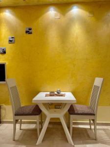una mesa blanca y dos sillas frente a una pared amarilla en Studio Duet 2002 en Budva