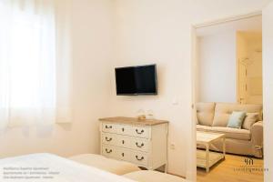 Living4Malaga Boutique Apartments في مالقة: غرفة معيشة مع تلفزيون وأريكة