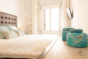 a bedroom with a large bed with two ottomans at Living4Malaga Boutique Apartments in Málaga