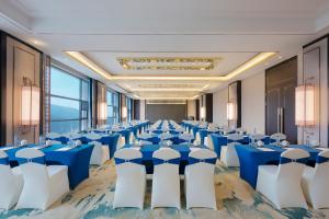 Pengze的住宿－彭泽远洲轩廷酒店，一个带蓝色桌子和白色椅子的大型宴会厅