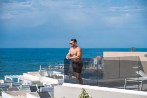 un hombre de pie en la parte superior de un edificio en Seafront villas I "Free" Heated pools & 100m to Sea, en La Canea