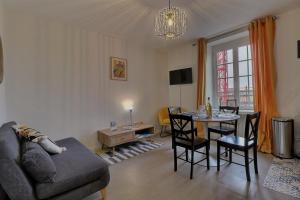 een woonkamer met een bank en een tafel met stoelen bij Les Mots Bleus in Dinard